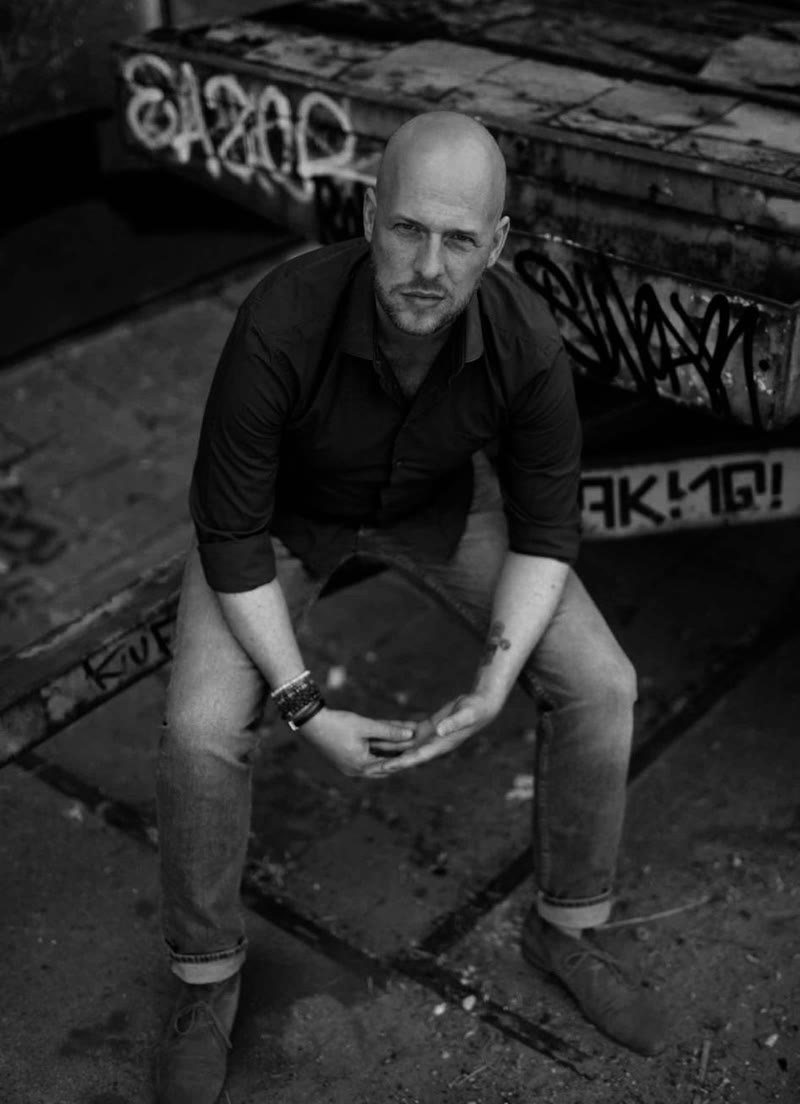 Dennis de Graaf zit op een trap met graffiti en kijkt in de camera