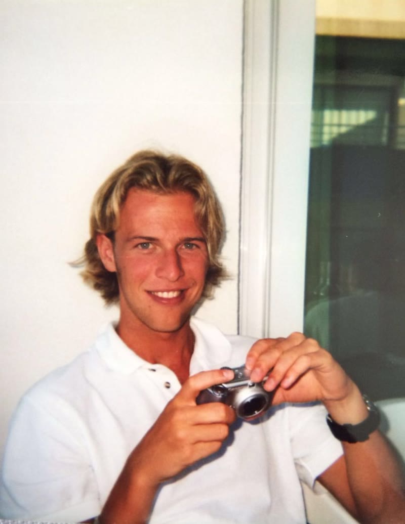 Dennis als jongen van achttien, in het wit, met een camera in Spanje